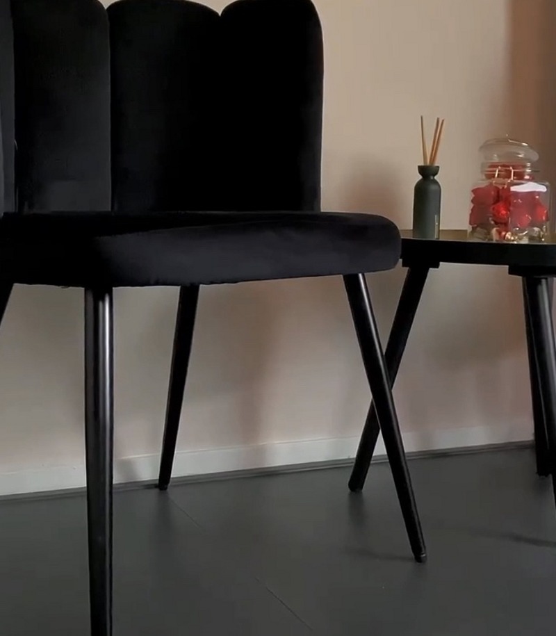 Zwarte fluwelen stoel met geschulpte rugleuning en een bijzettafel in de studio